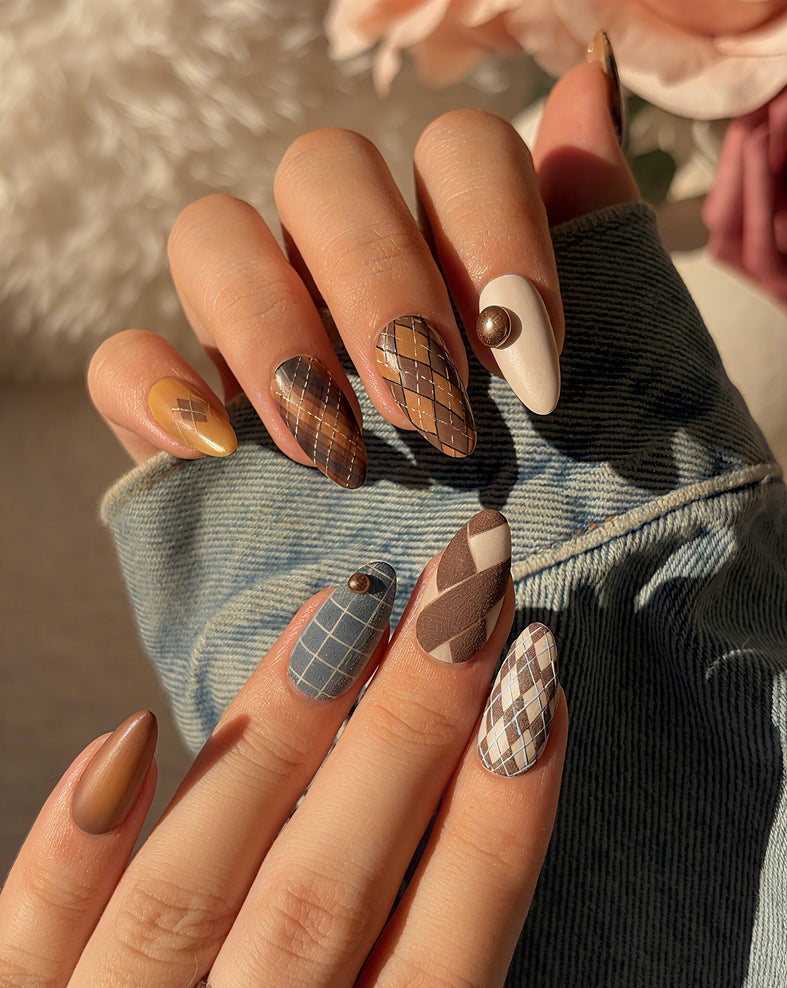Luxury press on nails in deep blue, brown, and caramel tones with plaid patterns and almond shape, showcasing a refined, heritage-inspired design