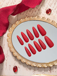 Matte velvet red press on nails in an elegant almond shape, displayed in a luxury flat lay with gold accents and a refined, timeless aesthetic.