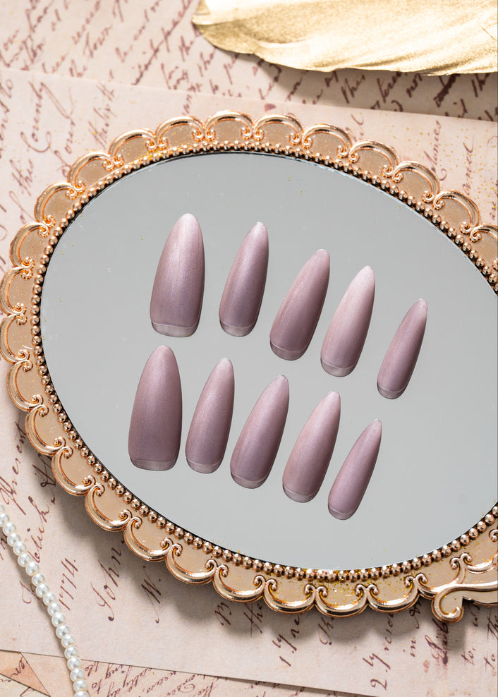 Luxury press on nails in a soft nude-violet color with a velvet finish and almond shape, presented in a refined minimal design by ZIYURA.