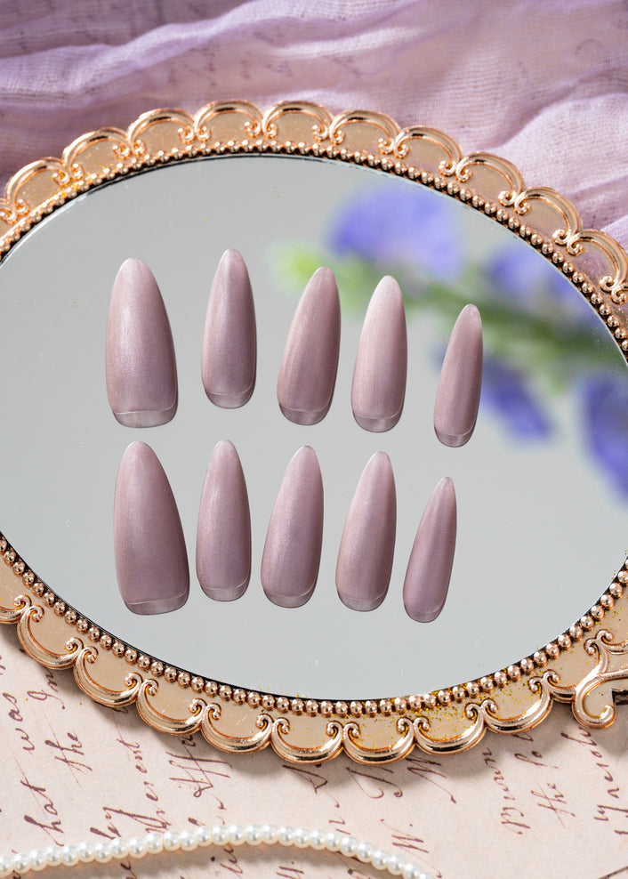 Luxury press on nails in a soft nude-violet color with a velvet finish and almond shape, presented in a refined minimal design by ZIYURA.