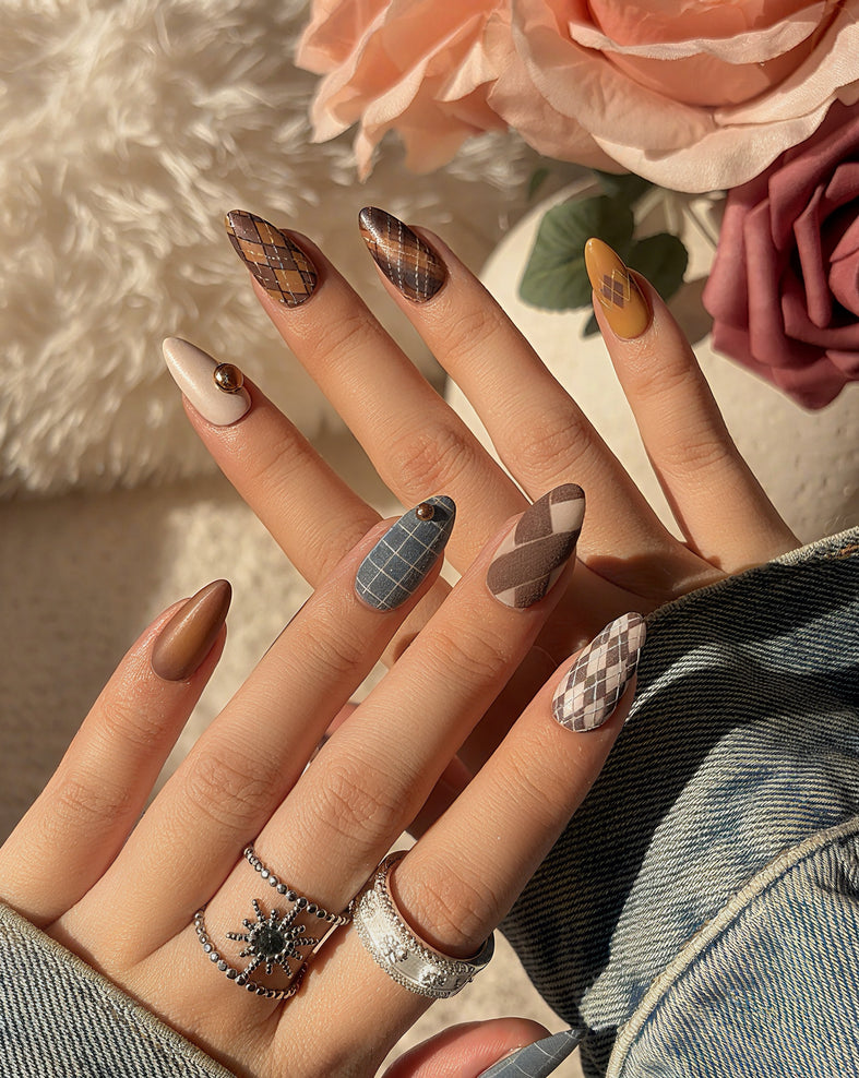 Luxury press on nails in deep blue, brown, and caramel tones with plaid patterns and almond shape, showcasing a refined, heritage-inspired design