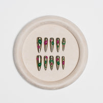 A set of metallic gold press-on nails with green and pink floral details, displayed on a round beige velvet ring stand against a light gray background.