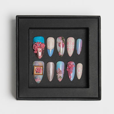 A set of 10 decorative press-on nails displayed inside a black square shadow box against a light gray background.