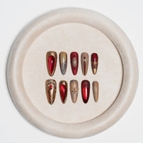 A set of 10 false press-on nails arranged in two rows on a round beige velvet tray, set against a clean white background.