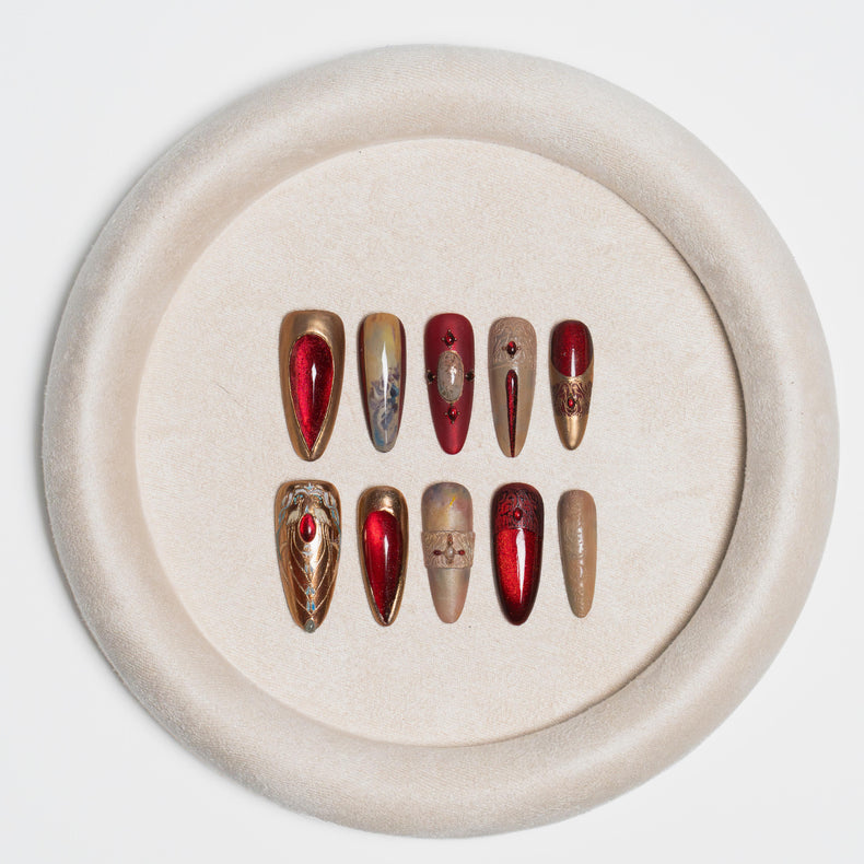 A set of 10 false press-on nails arranged in two rows on a round beige velvet tray, set against a clean white background.