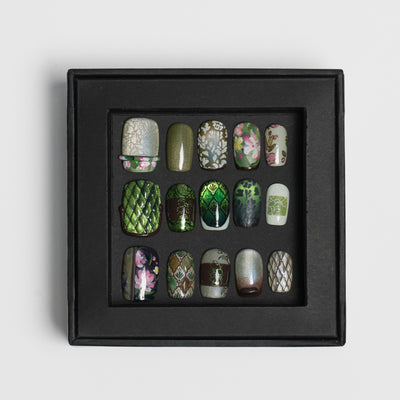 A set of 15 decorative press-on nails arranged in a 3x5 grid inside a black display tray, photographed on a clean light gray background.