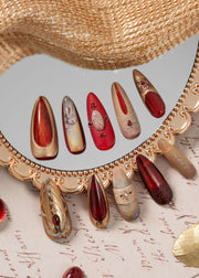 Luxury press on nails with ruby red, gold, and nude tones, inspired by ancient Egyptian art, displayed in an elegant decorative flat lay.